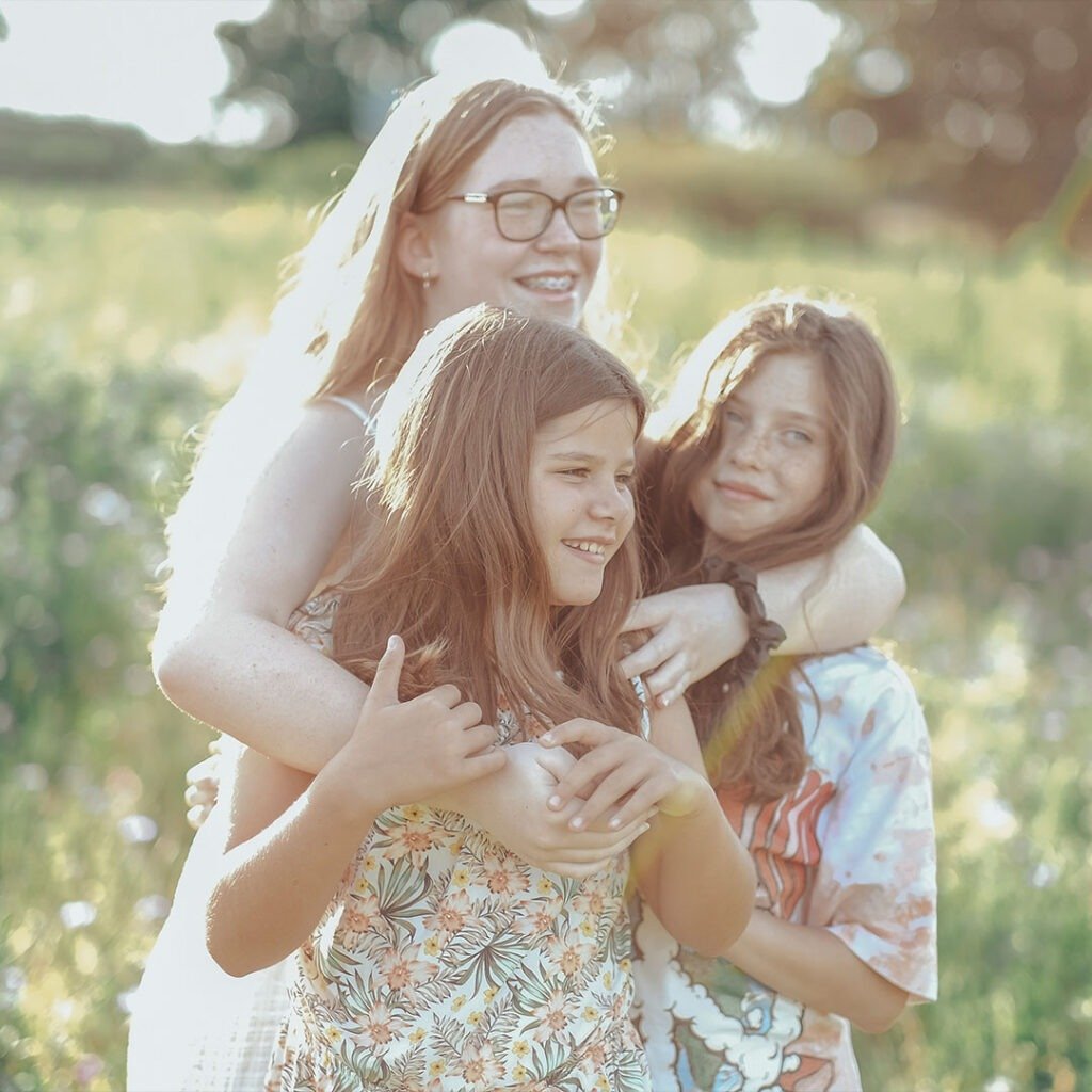 Three girls having fun in a field captured on a photoshoot