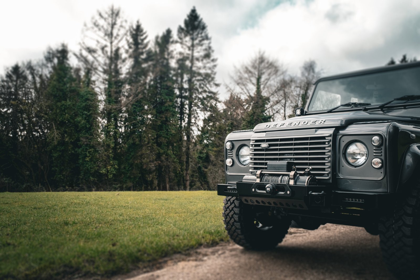 Beautiful Black Land Rover Defender driving through muddy Somerset woodland track